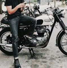 a man sitting on top of a motorcycle while looking at his cell phone