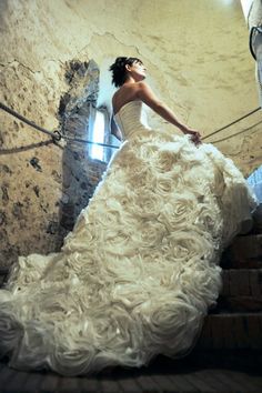 a woman in a white dress is standing on some stairs