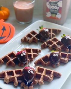 chocolate covered waffles on a white plate with strawberries in the shape of faces