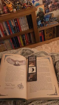 an open book sitting on top of a bed in front of a bookshelf