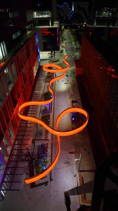 an aerial view of a city street at night with neon lights on the walkway and buildings in the background