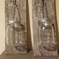 two mason jars with chains hanging from them on a wooden shelf next to a wall