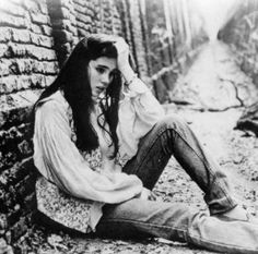 black and white photograph of a woman sitting on the ground next to a brick wall