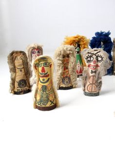 an assortment of wooden dolls sitting next to each other on a white surface with one doll in the middle