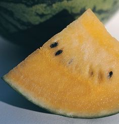 a piece of watermelon sitting on top of a white table next to a green bowl