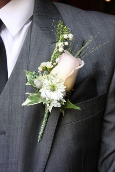 a boutonniere with white flowers and greenery is worn on a man's suit