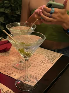 two martini glasses sitting on top of a table next to each other with sticks sticking out of them