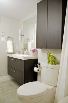 a white toilet sitting next to a sink in a bathroom under a window with curtains