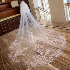 the bride is walking down the stairs in her wedding dress with a veil over her head