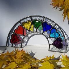 a stained glass arch with hearts on it in front of autumn leaves and grey sky