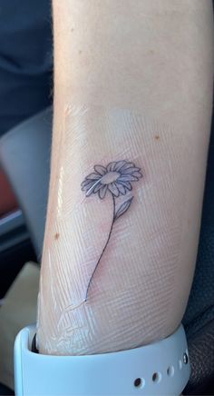 a small daisy tattoo on the left inner arm and wrist area, with one flower in it's center