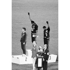 three men standing on top of a podium with their hands in the air while one man holds up his hand