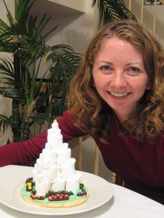 a woman sitting at a table with a cake shaped like a castle on top of it