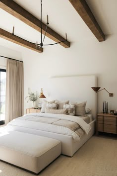 a large white bed sitting in a bedroom next to a wooden dresser and window sill