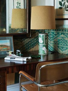 a desk with a chair and lamp in front of a mirror on the wall next to it