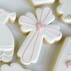 decorated cookies with white icing and pink bows on them are arranged in the shape of crosses