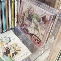 an assortment of anime dvds on display in a glass case with the covers pulled back