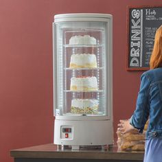 a woman standing in front of a cake display case