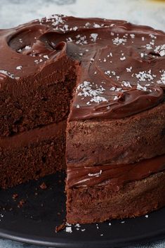 a chocolate cake on a black plate with one slice cut out and the other half eaten