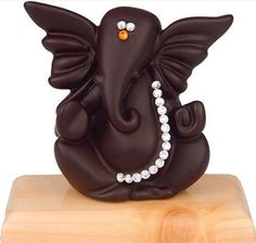 an elephant figurine with pearls on it's tail sitting on a wooden block