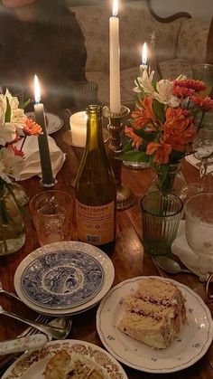 a table topped with plates and cake next to candles on top of a wooden table