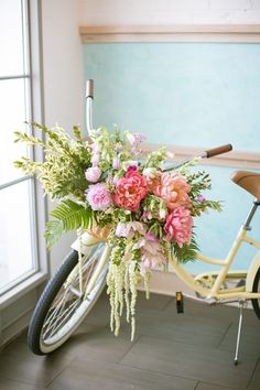 a bicycle with flowers in the basket is parked next to a wall and window sill