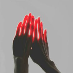 two hands with red fingers reaching up into the air