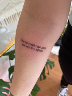 a person with a tattoo on their arm that says, the sun will rise and we will try again