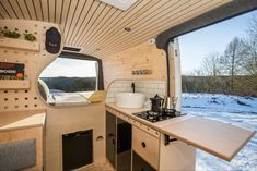 a kitchen area with sink, stove and window in the back ground is covered by snow