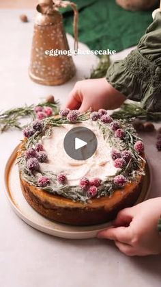 someone is decorating a cake with flowers and greenery on the top, while another person holds it in their hand