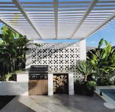 an outdoor kitchen with grill, oven and potted plants on the side of it