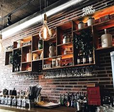 a bar with lots of bottles and glasses on the shelves, along with lights hanging from the ceiling