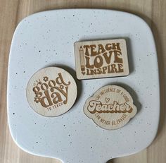 three wooden magnets with words on them sitting on a white plate next to each other