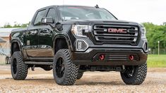 a black gmc truck parked in front of a barn