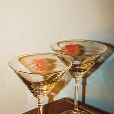 two martini glasses sitting on top of a wooden table