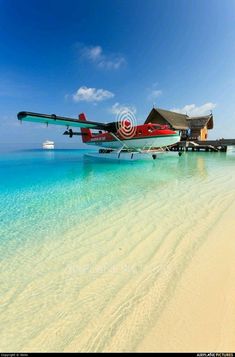 an airplane sitting on top of a sandy beach next to the ocean with clear blue water