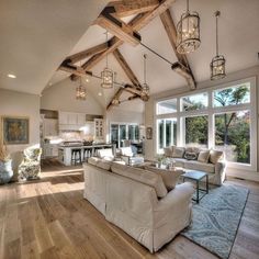 a living room filled with lots of furniture and large windows covered in wood beams