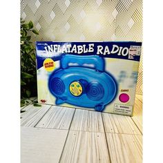 a blue inflatable radio sitting on top of a wooden table next to a potted plant