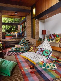 a living room filled with lots of colorful pillows and blankets on top of the floor