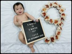 a baby sitting on a bed holding a sign