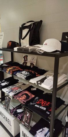 there are many items on the shelves in this store, including t - shirts and hats