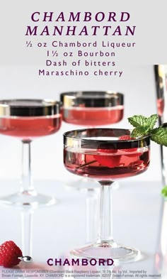 two glasses filled with red liquid and garnished with raspberries