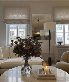 a living room filled with furniture and a table topped with a vase full of flowers