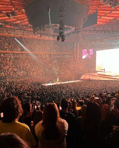 a large crowd at a concert with confetti in the air and people standing on the stage