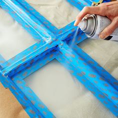 a person spray painting an old frame with blue paint