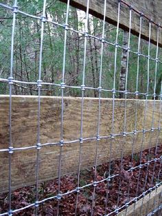 the fence is made of wood and metal wire, along with leaves on the ground