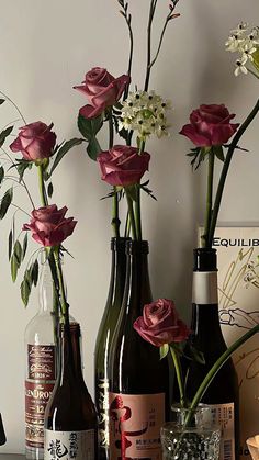 three wine bottles with flowers in them sitting on a table