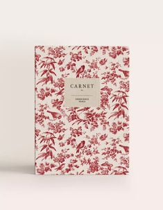 a red and white book with flowers on the cover, in front of a white background