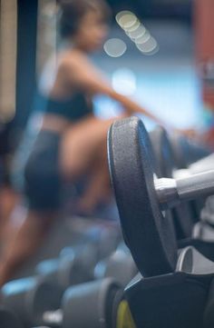 a woman is running on a treadmill in the gym with her leg up and other equipment behind her