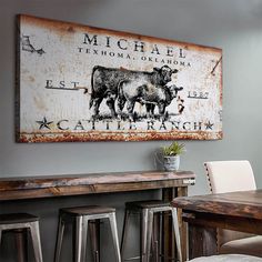 an old metal sign hangs on the wall above a wooden table and bar stools